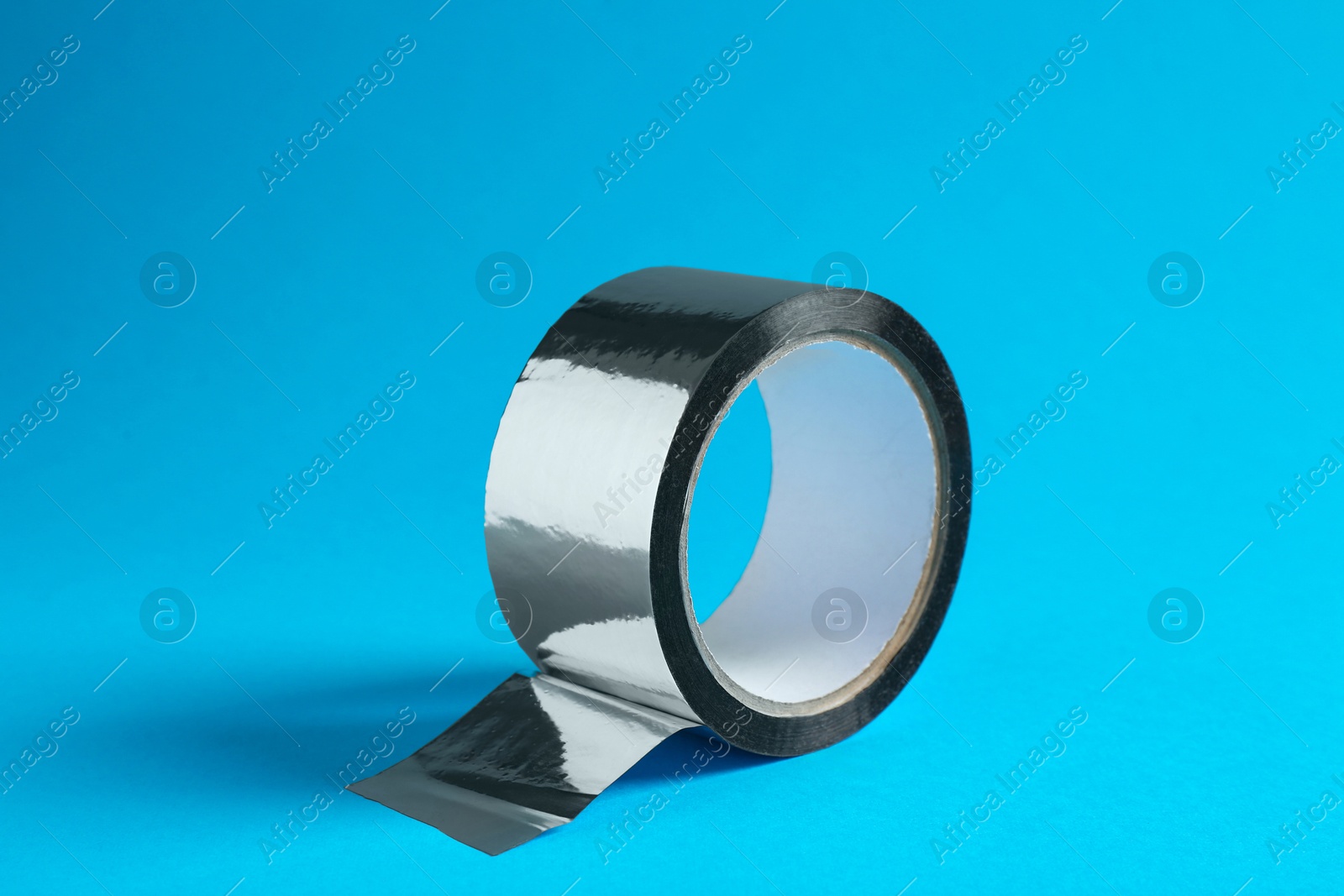 Photo of Roll of silver adhesive tape on light blue background