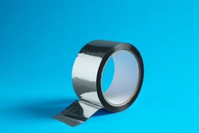 Roll of silver adhesive tape on light blue background