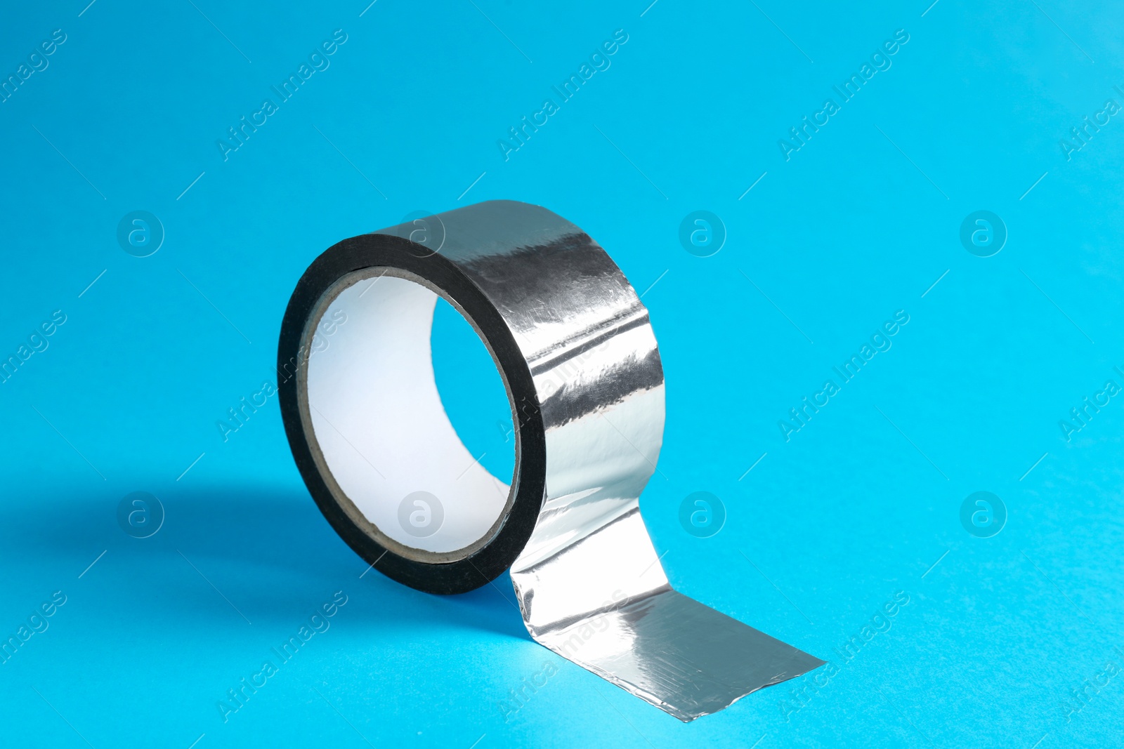 Photo of Roll of silver adhesive tape on light blue background