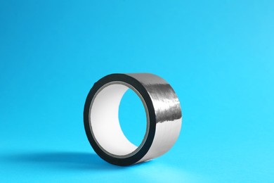 Photo of Roll of silver adhesive tape on light blue background