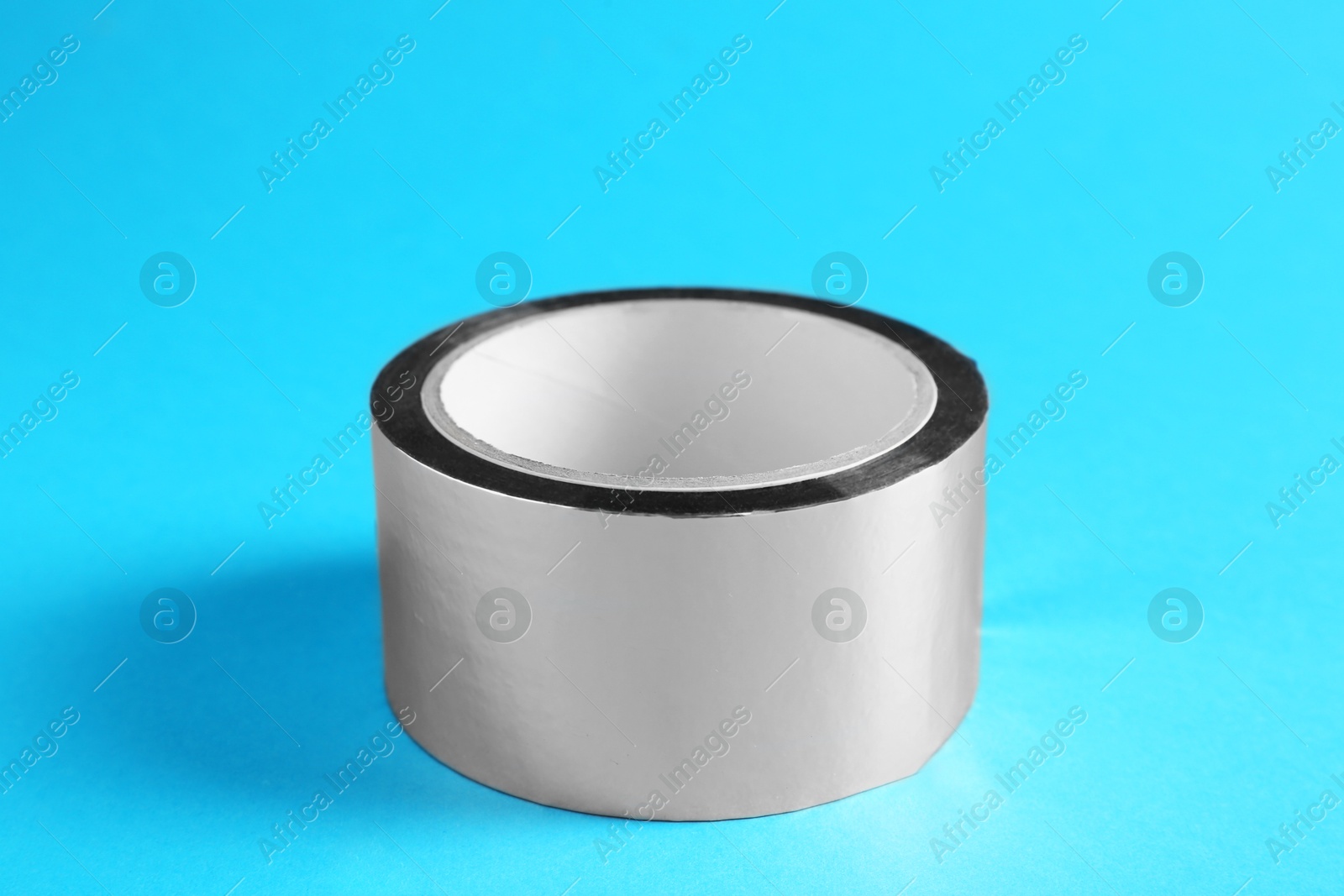 Photo of Roll of silver adhesive tape on light blue background