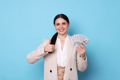 Photo of Banker with dollar banknotes showing thumbs up on light blue background