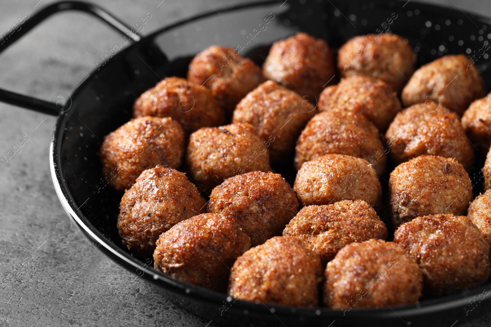 Photo of Tasty meatballs in baking dish on grey table, closeup