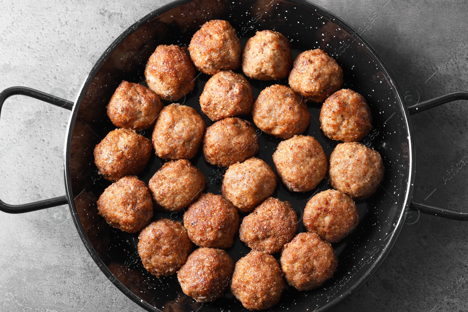 Photo of Tasty meatballs in baking dish on grey table, top view