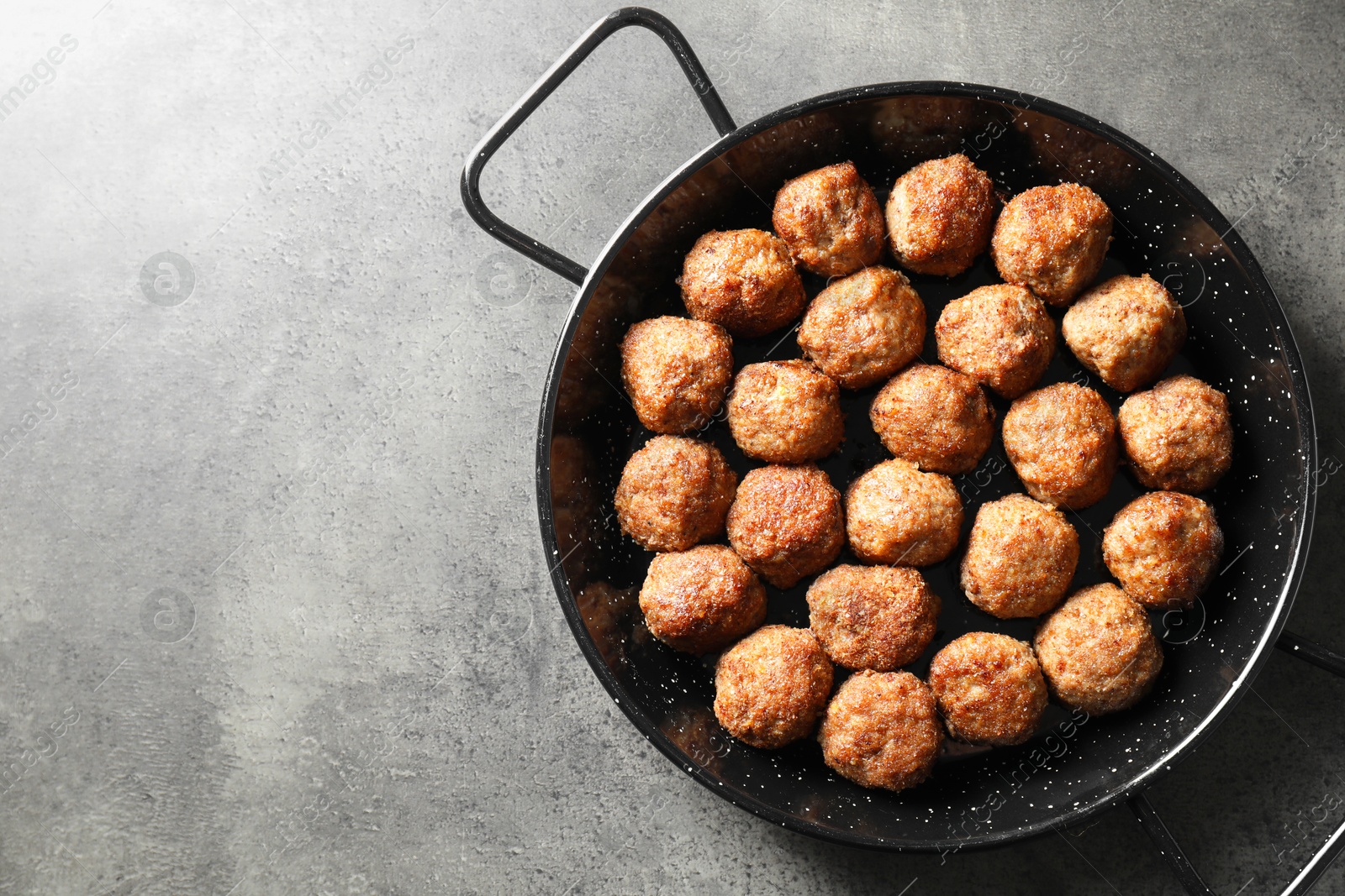 Photo of Tasty meatballs in baking dish on grey table, top view. Space for text