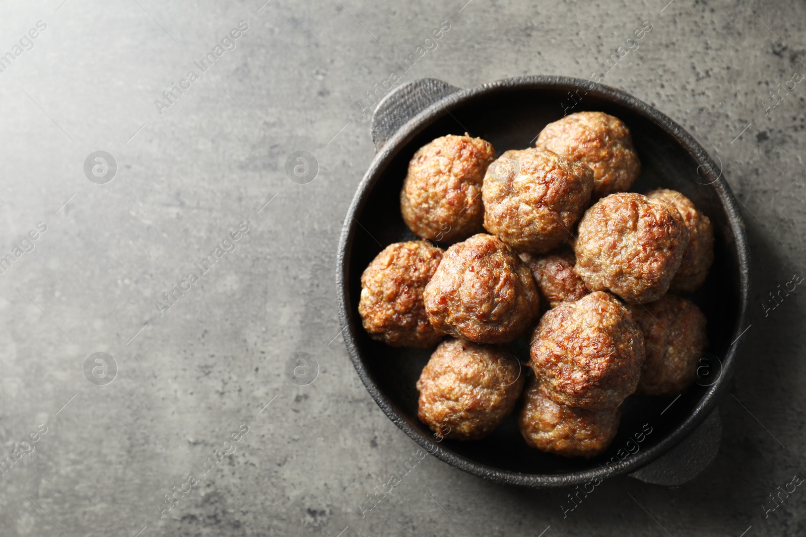 Photo of Tasty meatballs in baking dish on grey table, top view. Space for text