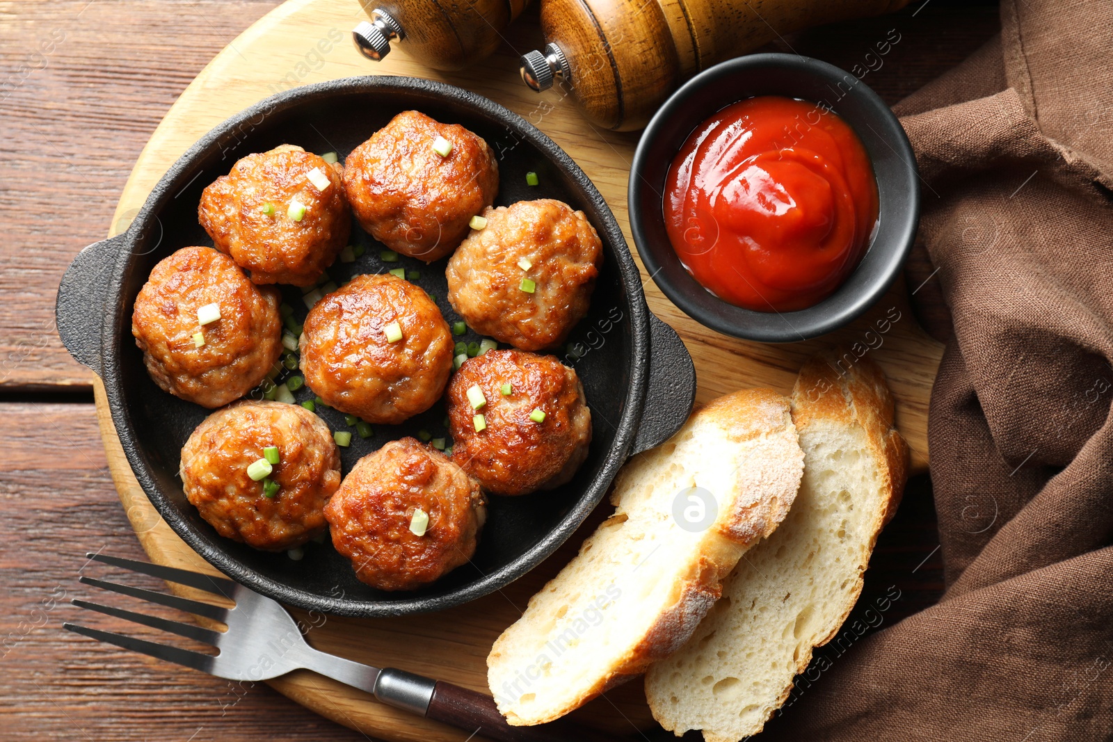 Photo of Tasty meatballs with green onion in baking dish served on wooden table, flat lay