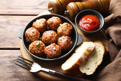 Photo of Tasty meatballs with green onion in baking dish served on wooden table