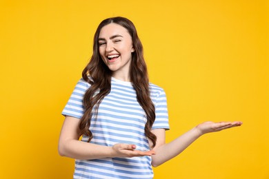 Photo of Happy woman welcoming friends or guests on yellow background