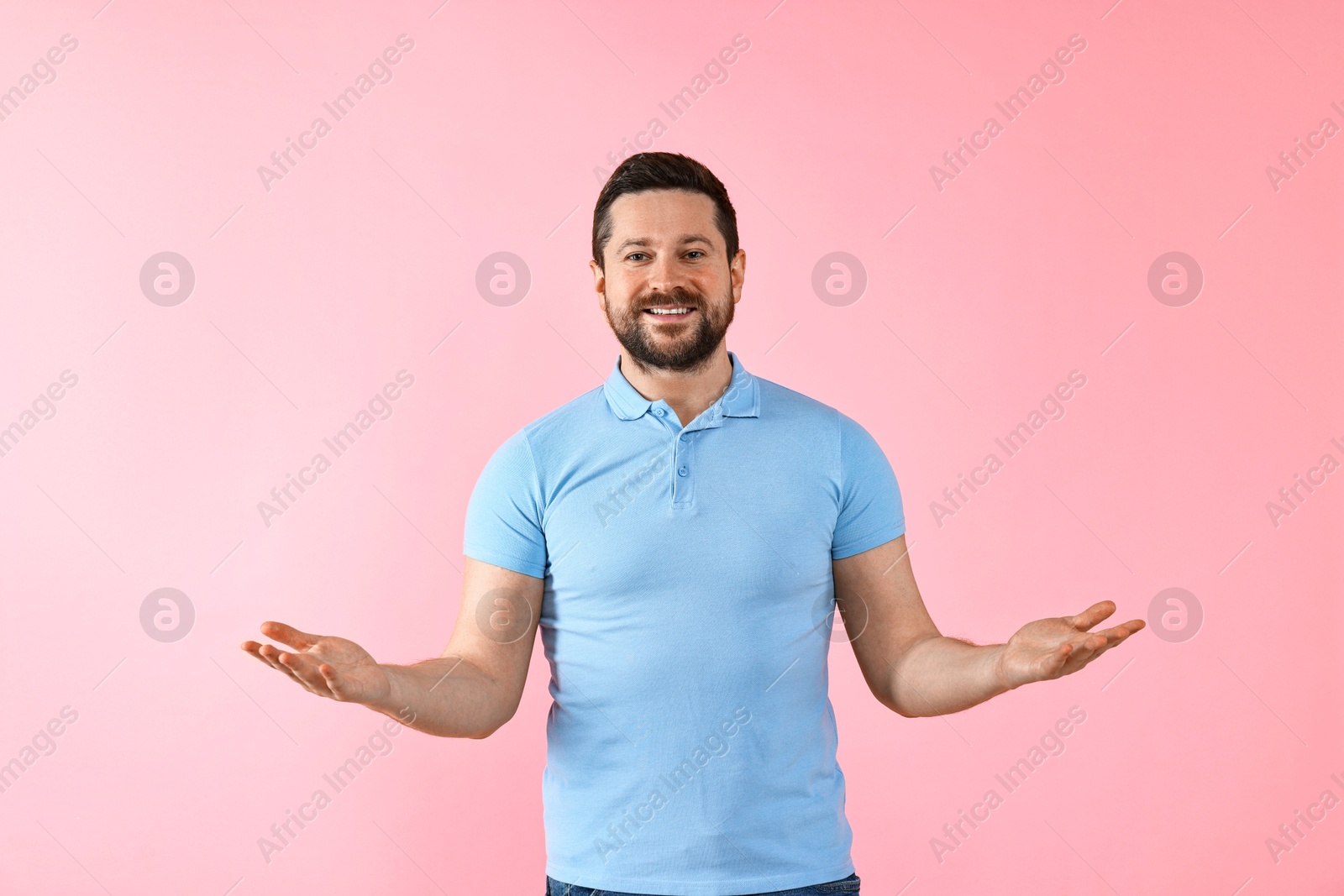 Photo of Happy man welcoming friends or guests on pink background