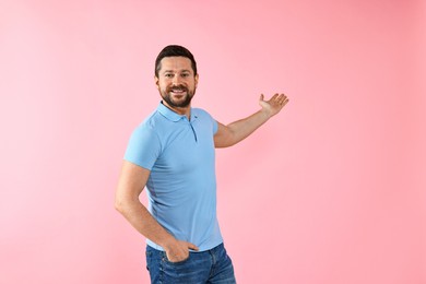 Photo of Happy man welcoming friends or guests on pink background