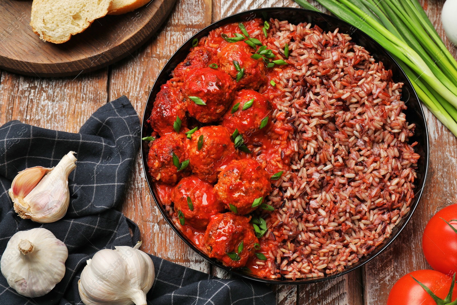 Photo of Tasty meatballs with sauce, brown rice and products on wooden table, flat lay