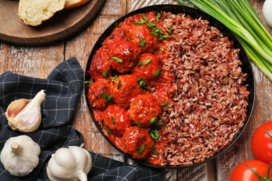 Photo of Tasty meatballs with sauce, brown rice and products on wooden table, flat lay