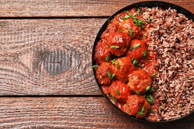 Photo of Tasty meatballs with sauce and brown rice on wooden table, top view. Space for text