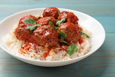 Photo of Tasty meatballs with sauce and rice on light blue wooden table, closeup