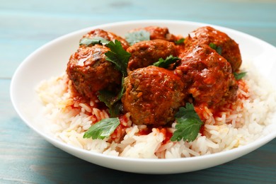 Photo of Tasty meatballs with sauce and rice on light blue wooden table, closeup