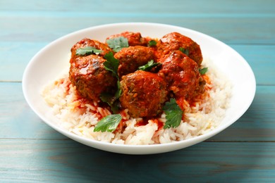 Photo of Tasty meatballs with sauce and rice on light blue wooden table, closeup