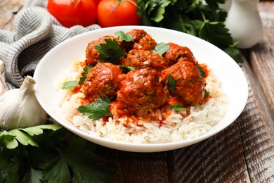 Photo of Tasty meatballs with sauce, rice and products on wooden table, closeup