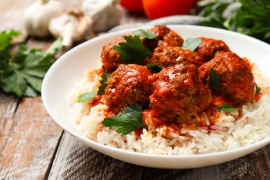 Photo of Tasty meatballs with sauce, rice and products on wooden table, closeup