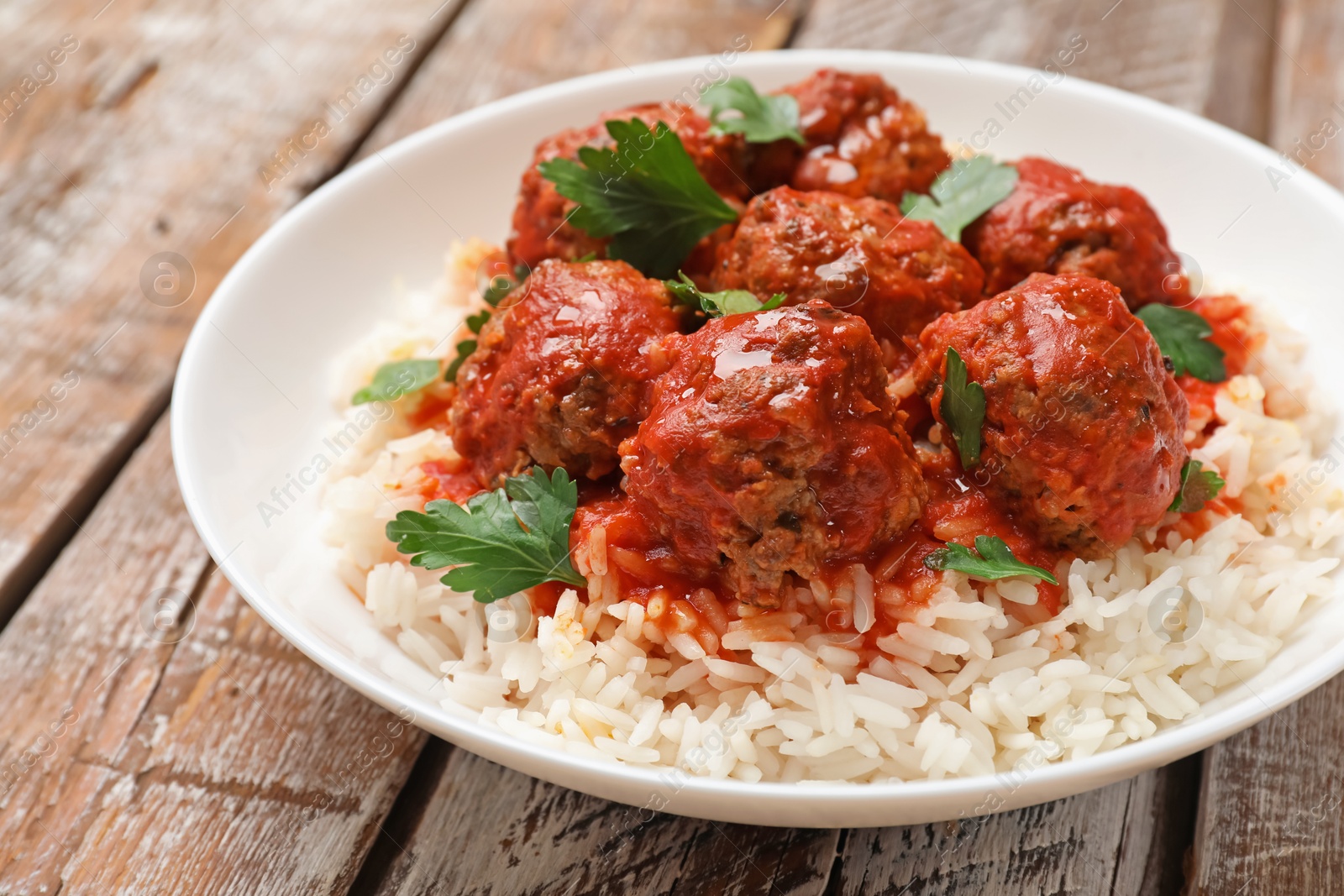 Photo of Tasty meatballs with sauce and rice on wooden table, closeup