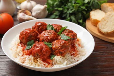 Photo of Tasty meatballs with sauce, rice and products on wooden table, closeup