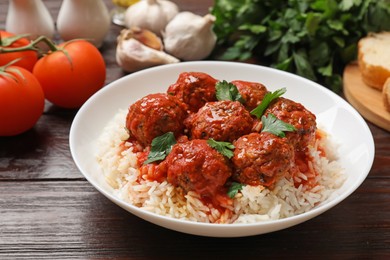 Photo of Tasty meatballs with sauce, rice and products on wooden table, closeup