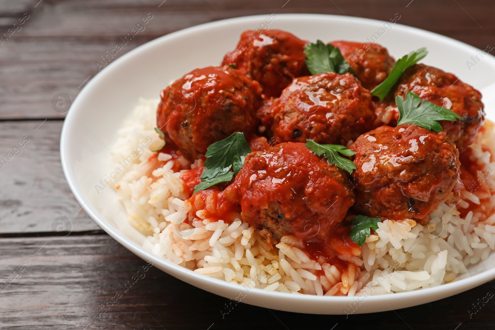 Photo of Tasty meatballs with sauce and rice on wooden table, closeup