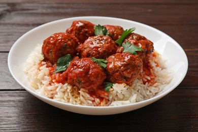 Photo of Tasty meatballs with sauce and rice on wooden table, closeup