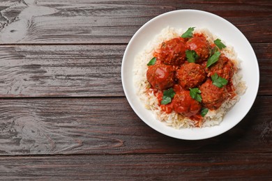 Photo of Tasty meatballs with sauce and rice on wooden table, top view. Space for text