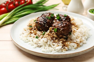 Photo of Delicious rice with meatballs, sauce and green onions on white wooden table, closeup