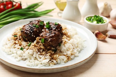 Photo of Delicious rice with meatballs, sauce and green onions on white wooden table, closeup