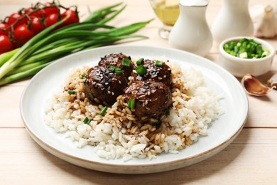 Photo of Delicious rice with meatballs, sauce and green onions on white wooden table, closeup