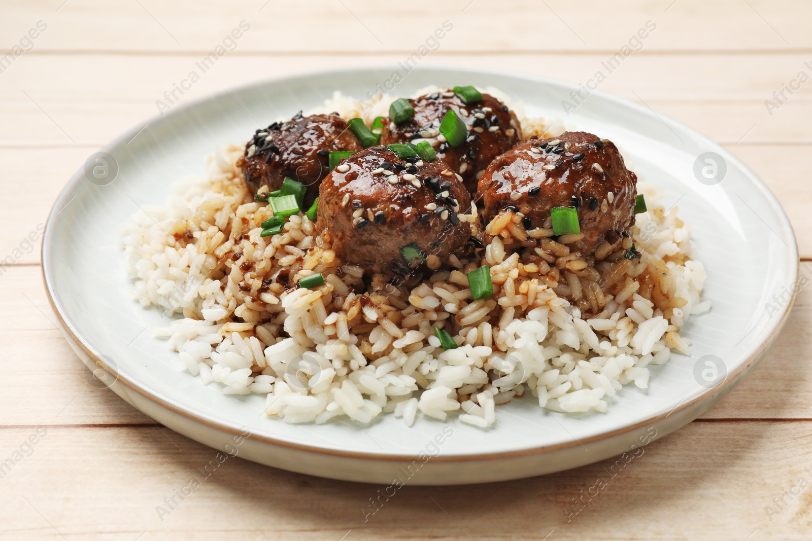 Photo of Delicious rice with meatballs, sauce and green onions on white wooden table, closeup