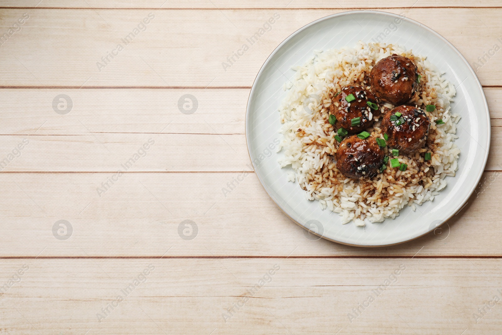 Photo of Delicious rice with meatballs, sauce and green onions on white wooden table, top view. Space for text