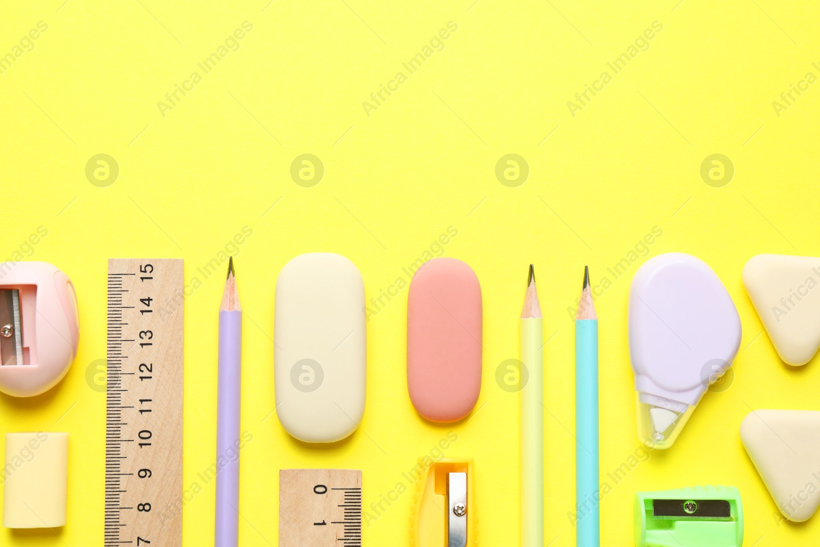 Photo of Erasers and other stationery on yellow background, flat lay. Space for text