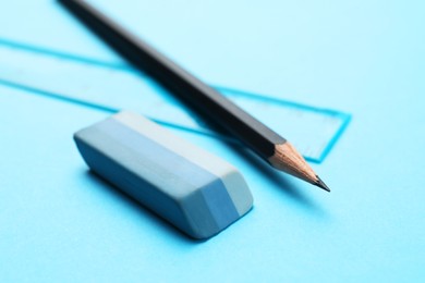 Photo of Eraser, pencil and ruler on light blue background, closeup