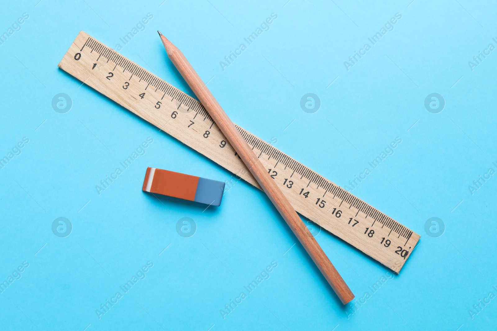 Photo of Eraser, pencil and ruler on light blue background, top view