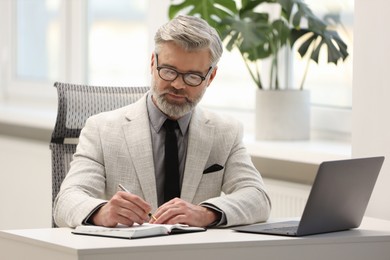 Photo of Banker taking notes at desk in office