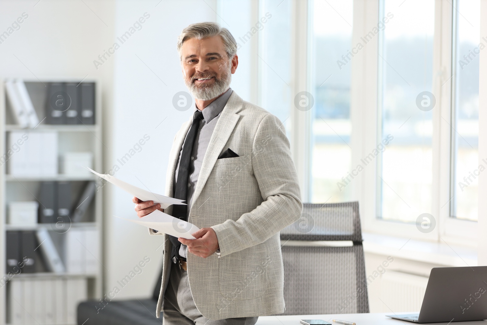 Photo of Banker with documents near desk in office