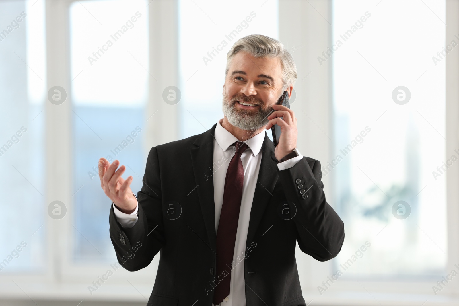 Photo of Happy banker talking on smartphone in office