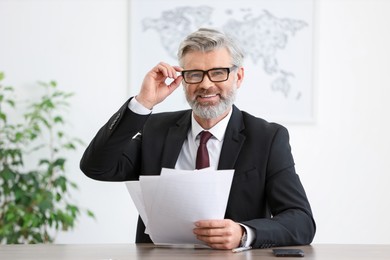 Photo of Portrait of banker with documents at desk in office