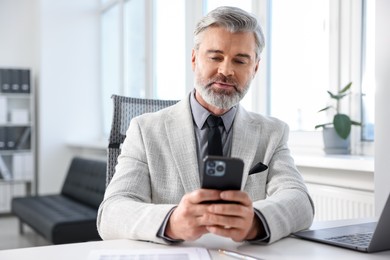 Photo of Banker with smartphone at desk in office