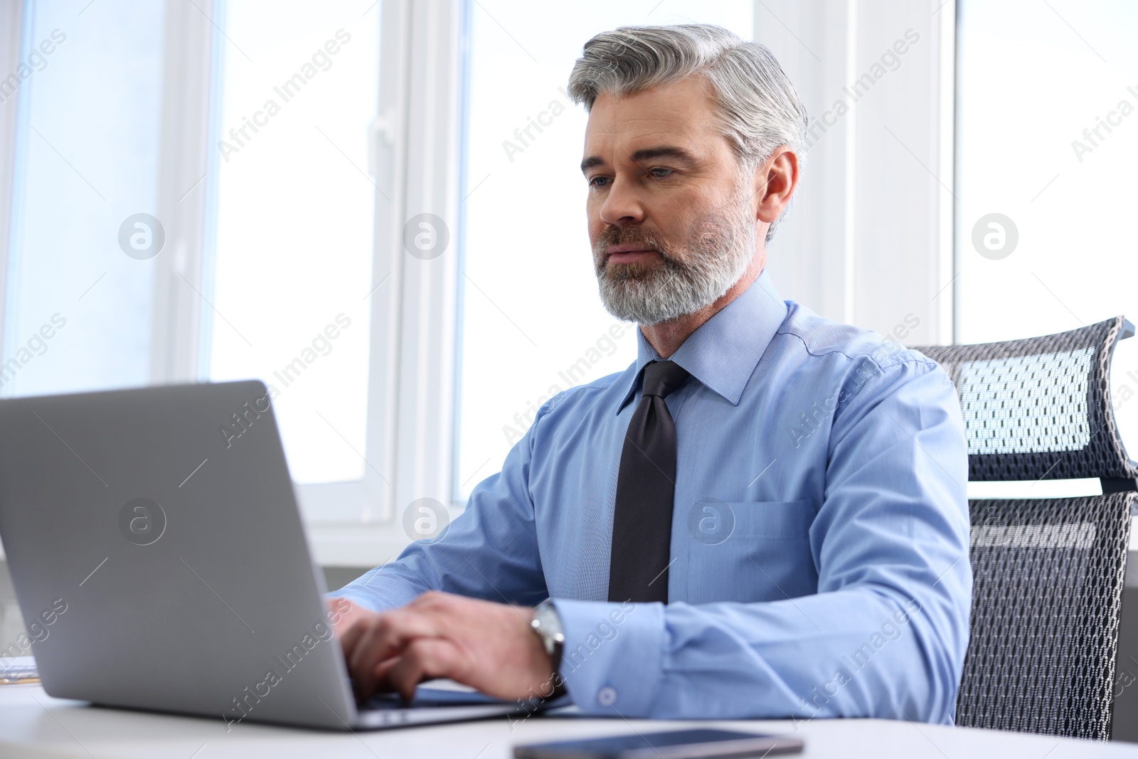 Photo of Banker working on laptop at desk in office