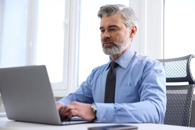 Photo of Banker working on laptop at desk in office