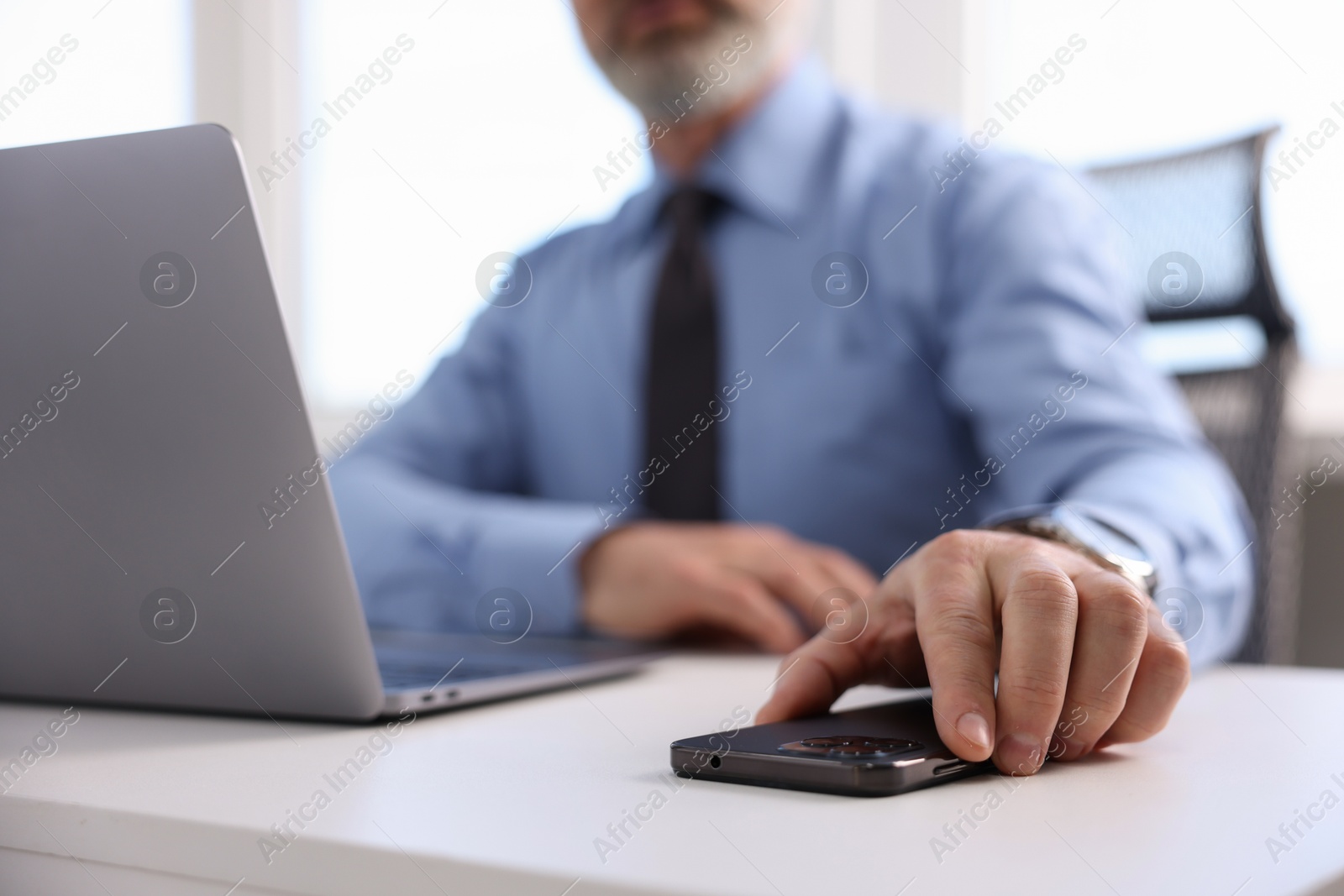 Photo of Banker with smartphone at desk in office, closeup