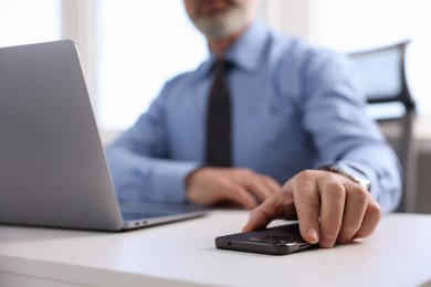 Photo of Banker with smartphone at desk in office, closeup