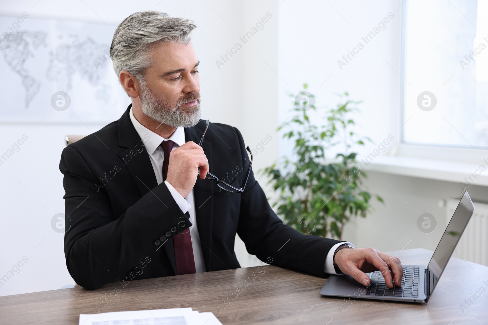 Photo of Banker with glasses working on laptop at desk in office