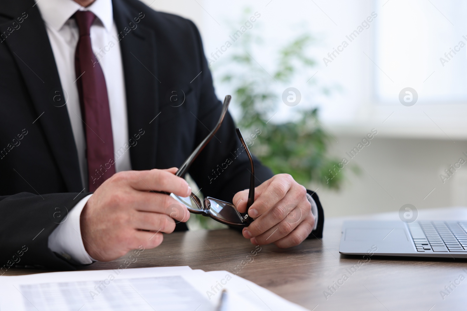 Photo of Banker with glasses at wooden desk in office, closeup