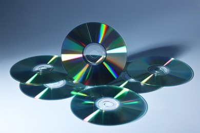 Photo of Many shiny compact discs on dusty blue background