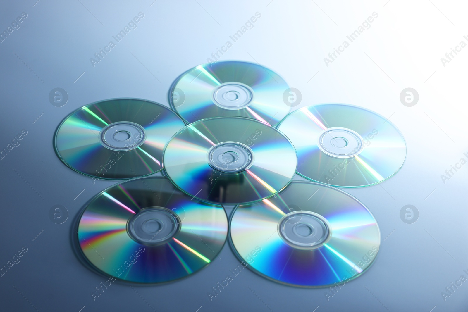 Photo of Many shiny compact discs on dusty blue background